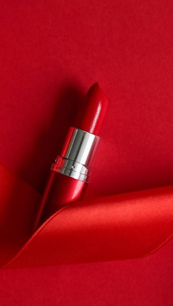 Luxury lipstick and silk ribbon on red holiday background, make- - Foto, Imagen