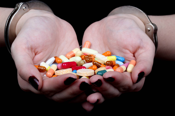 mit gefesselten Händen und Medikamententabletten auf schwarzem Hintergrund - Foto, Bild