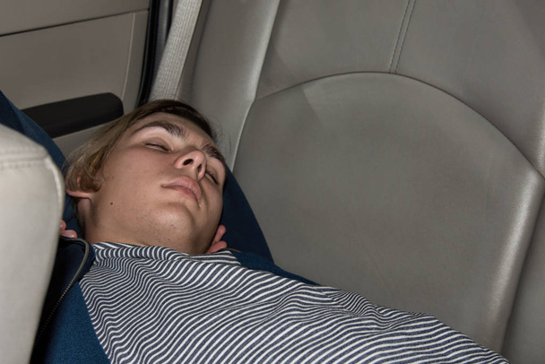 junger attraktiver Kerl schläft im Auto auf dem Rücksitz. - Foto, Bild