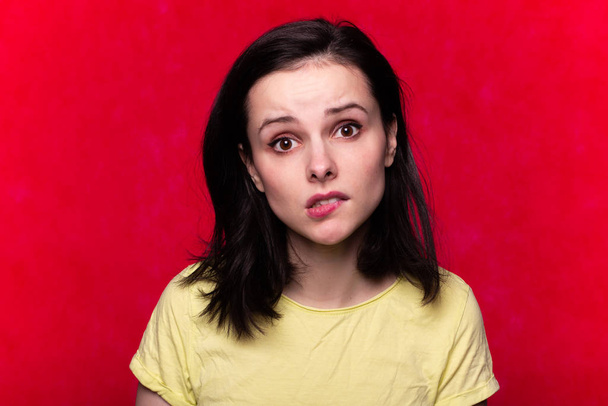 kaunis emotionaalinen tyttö t-paidassa punaisella taustalla
 - Valokuva, kuva
