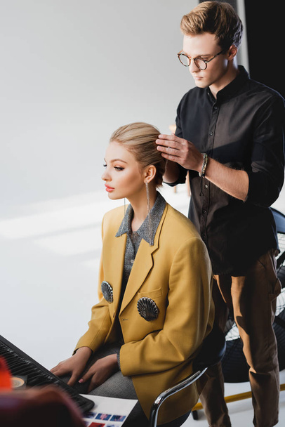 handsome hairstylist doing hairstyle to stylish model on backstage   - Фото, зображення