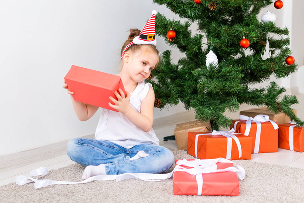 Kid opening Xmas presents. Child under Christmas tree with gift boxes. - Foto, imagen