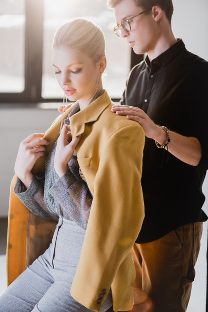 όμορφος στυλίστας φορώντας σακάκι σε κομψό μοντέλο στα παρασκήνια - Φωτογραφία, εικόνα