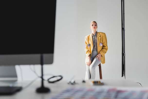 selective focus of stylish model posing and sitting on stool on backstage  - Fotoğraf, Görsel
