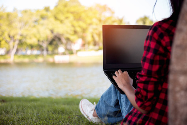 University student using laptop under tree. Education concept. - Photo, Image
