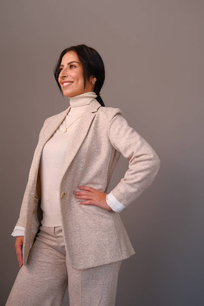 Young smiling woman in beige outfit posing in studio - Photo, Image