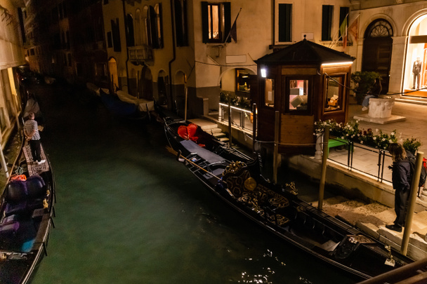 VENICE, ITALY - SEPTEMBER 24, 2019: canal with gondolas near ancient building at night in Venice, Italy  - Fotoğraf, Görsel