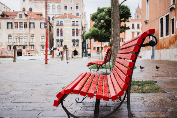 selective focus of red bench and ancient buildings on background in Venice, Italy  - Photo, Image