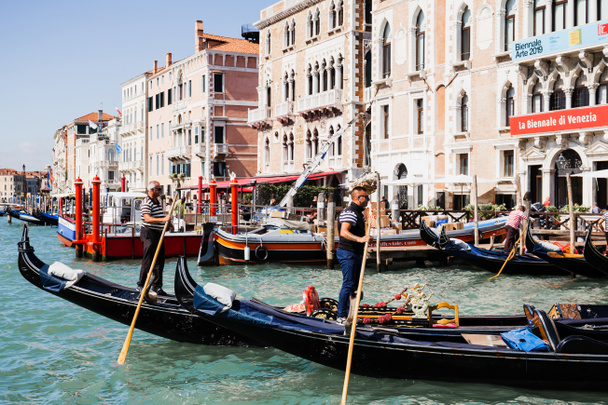 VENICE, ITALY - SEPTEMBER 24, 2019: side view of gondoliers floating on gondolas in Venice, Italy  - Photo, image