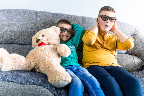 Cute boys watching scary movie with 3d glasses, together with teddy bear toy - Foto, imagen