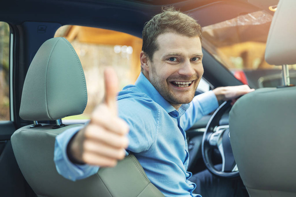muž sedí v autě a ukazuje palec nahoru gesto - Fotografie, Obrázek