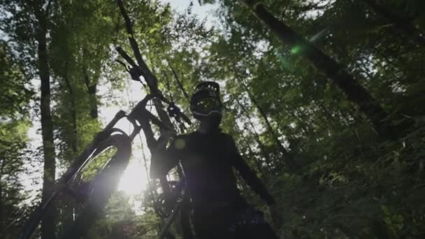 Mountain biker carries his bike through forest in super slow motion - Filmagem, Vídeo