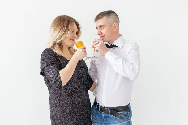 Tatiller, noeller, sevgililer günü ve yeni yıl konsepti - kadın ve erkek beyaz arka planda bir bardakta şarap içip kutluyor - Fotoğraf, Görsel