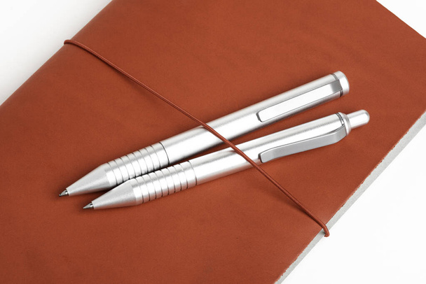 Cubierta de diario de cuero rojo con dos bolígrafos
 - Foto, Imagen