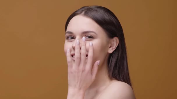 Het meisje wrijft zachtjes haar gezicht met haar handen genietend van het proces van huidcrème - Video