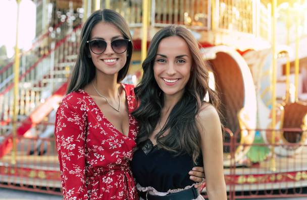 two stylish and beautiful girlfriends smiling on attraction background - Foto, immagini