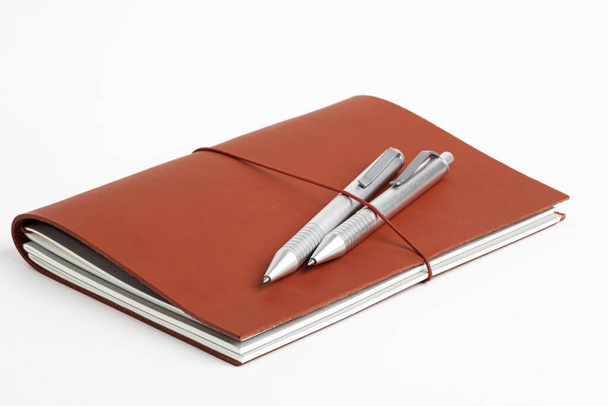 Cubierta de diario de cuero rojo con dos bolígrafos
 - Foto, Imagen