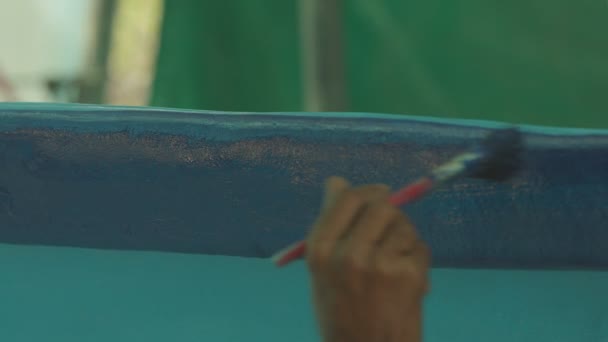 Közelkép a fiatal férfi kezét festés fa halászhajó a kikötőben. - Felvétel, videó