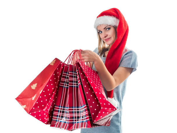 Young pretty woman in santa hat holding christmas bags - Fotoğraf, Görsel