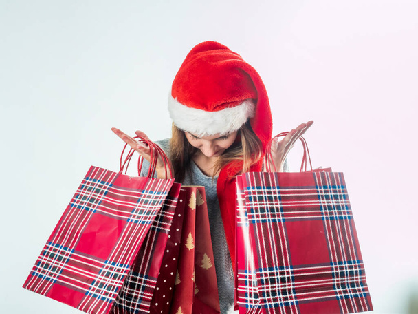 Young pretty woman in santa hat holding christmas bags - Fotoğraf, Görsel