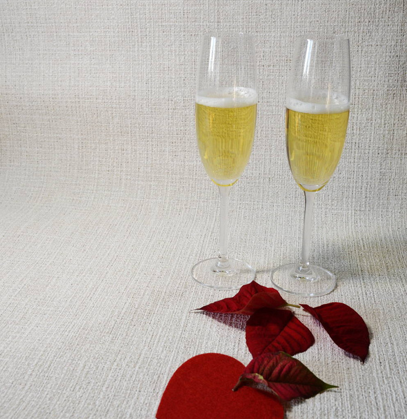 Urlaub. auf hellem Hintergrund in Form einer Matte stehen Glasgläser mit Champagner und roten frischen Blättern. - Foto, Bild