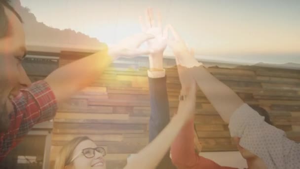 Animation of group of office workers celebrating, doing high fives with sun setting in countryside in the foreground - Video