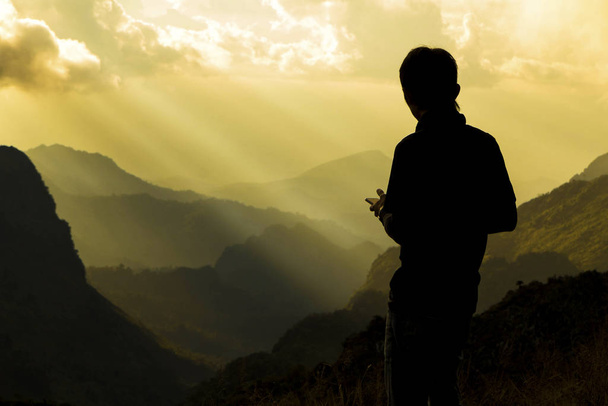 Dağın tepesindeki bir adamın silueti. Başarı ve motivasyon kavramı - Fotoğraf, Görsel