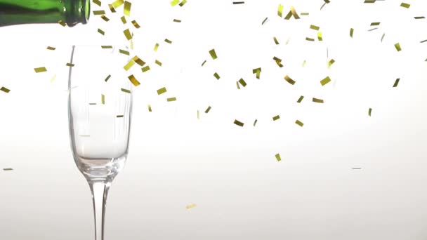 Animation of champagne being poured into a glass from a bottle with golden confetti falling during New Year Eve celebrations on white background - Imágenes, Vídeo