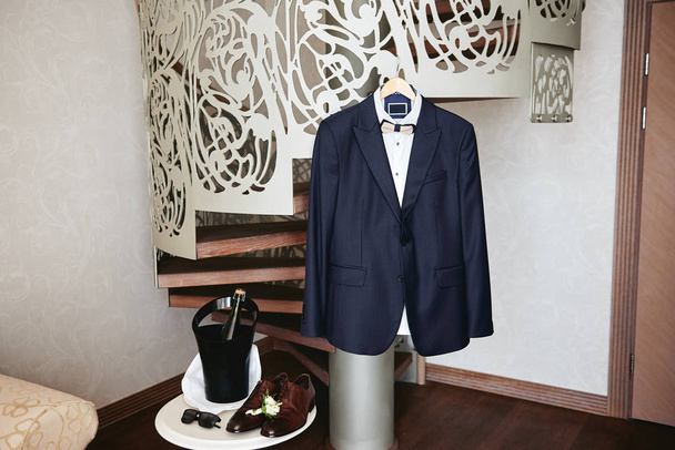 Elegant male suit with white shirt hanging on stairs, brown male - Photo, Image