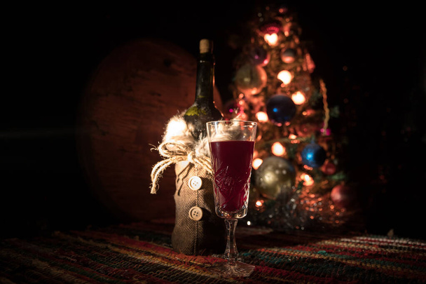 Red wine in crystal glass with bottle on colorful carpet with creative New Year artwork decorations. Copy space - Foto, Imagen