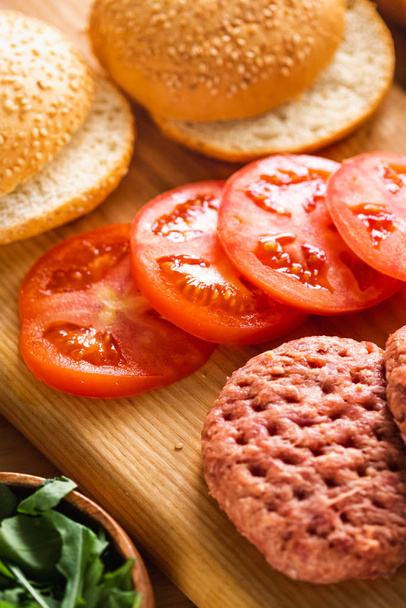 Buns, raw beef cutlets, tomatoes and herbs for burgers cooking. - Photo, Image