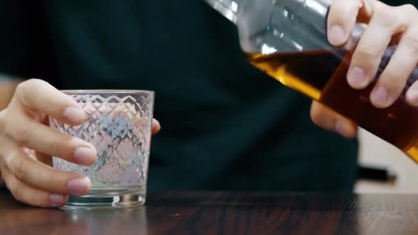 Blízký: osamělý muž nalévá whisky ve sklenici z láhve a pití - Záběry, video