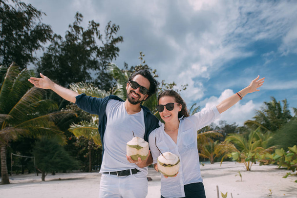 Šťastný pár milenců s koktejly na tropické pláži. - Fotografie, Obrázek