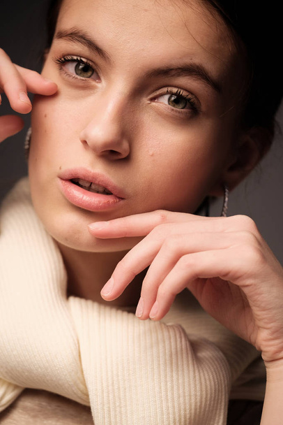 Pretty woman with nude makeup and beige sweater posing in studio - Foto, afbeelding