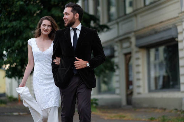 Newlyweds couple walking in daytime on urban background - Фото, изображение