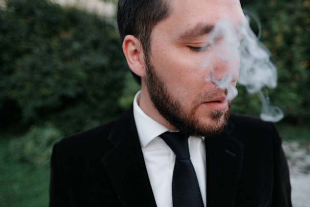 Stylish man in suit smoking outdoors - Photo, Image