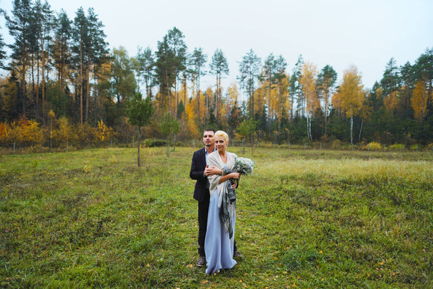 Pretty newlyweds couple posing in park - Zdjęcie, obraz