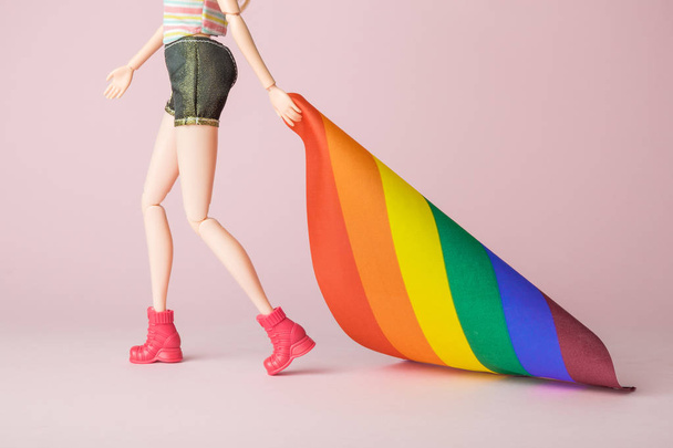 Lesbian girl doll walking and holding rainbow flag. Gay pride parade abstract on rose. - Photo, Image