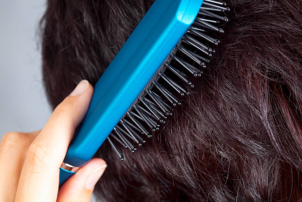 брюнетка жінка розчісує волосся
 - Фото, зображення