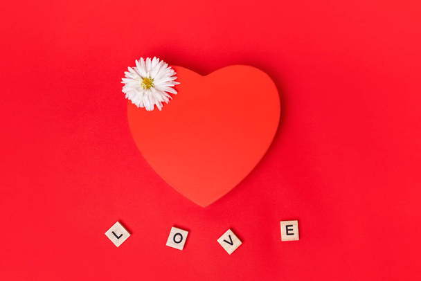 Love Inschrift mit rotem Herz auf rotem Hintergrund. Blick von oben. Vorlage Design der Postkarte. Valentinstag-Konzept. - Foto, Bild