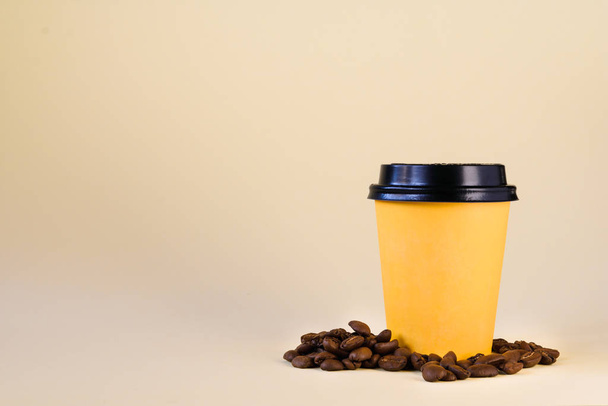 gelbe Papptasse mit Kaffeekörnern auf gelbem Hintergrund - Foto, Bild
