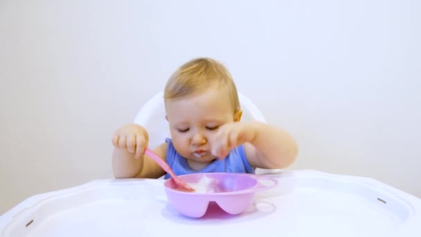 Zum ersten Mal in seinem Leben isst ein Kind selbst Brei. das Kind isst zum ersten Mal allein - Filmmaterial, Video