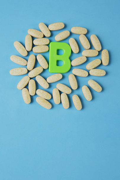 Vitamina B en pastillas con la letra B sobre fondo azul. Acostado. Vista superior. Copiar espacio. Foto vertical
. - Foto, Imagen