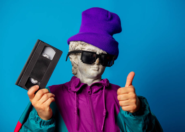 antique statue dressed in trendy clothes of the nineties holds V - Foto, immagini
