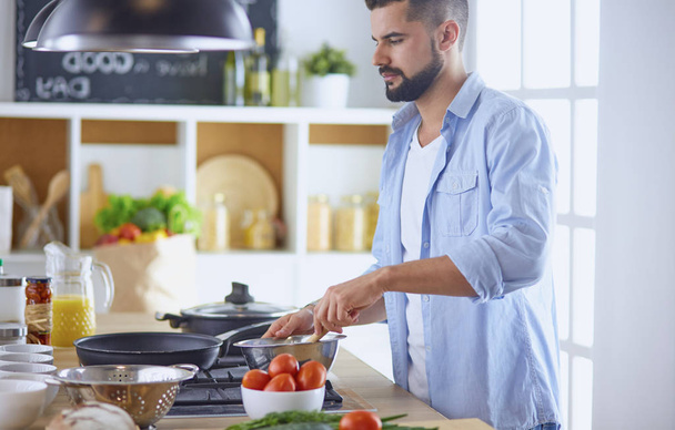 Улыбающийся и уверенный шеф-повар стоит на большой кухне - Фото, изображение