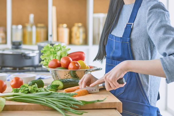A young woman prepares food in the kitchen. Healthy food - vege - 写真・画像