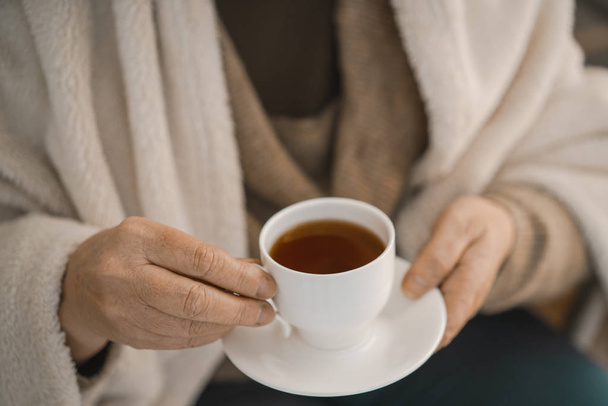 Ženské ruce drží bílý pohár s horkým čajem - Fotografie, Obrázek