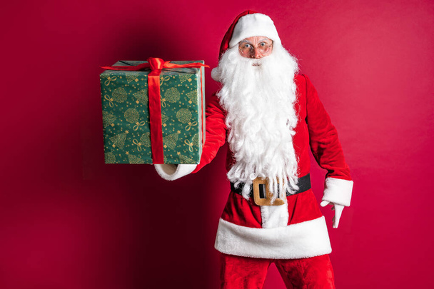 Photo of kind Santa Claus giving xmas present and looking at camera - Photo, image