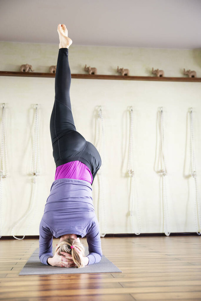 Yoga yapan ve kafa üstünde duran bir kadın. Fiziksel ve zihinsel sağlık kavramı, mutlu yaşam ve refah. - Fotoğraf, Görsel