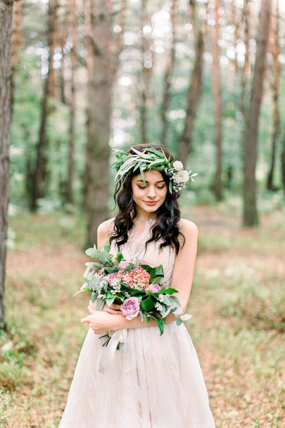 Báječná brunetka usmívající se nevěsta se svatební kyticí tráví čas v lese. Poloviční portrét. - Fotografie, Obrázek